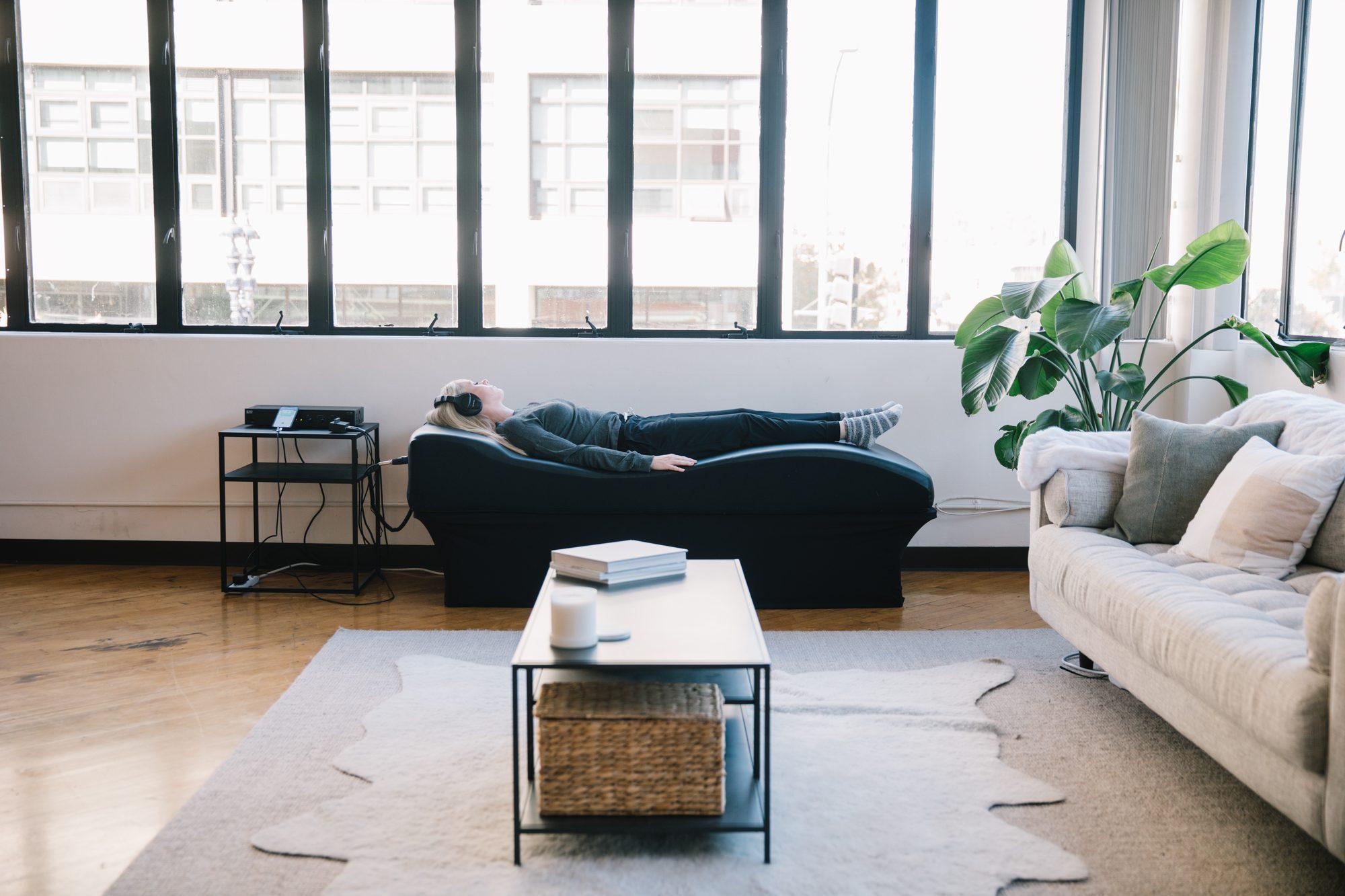 The vibroacoustic table set up in a living room next to a couch and coffee table